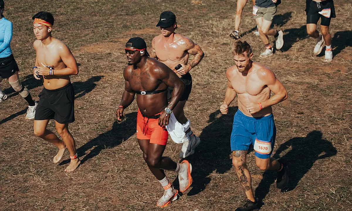 Shirtless male runners racing across dry grass in an outdoor race