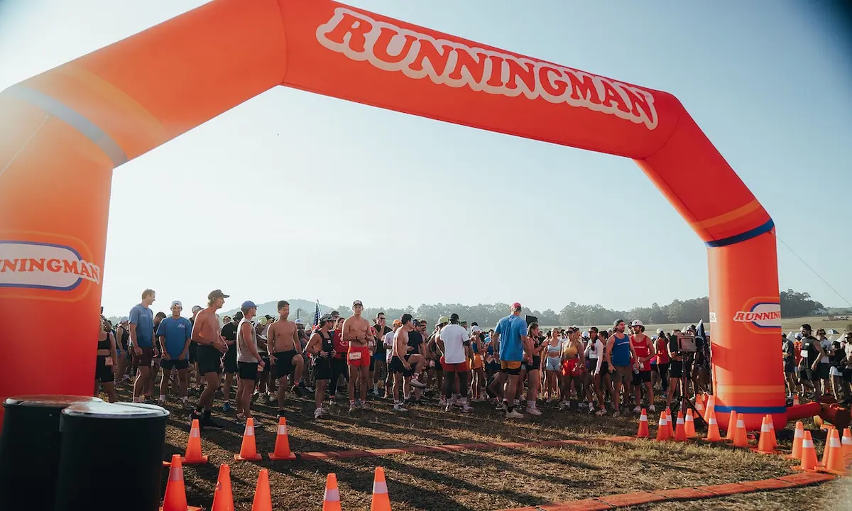 Runners gathered at orange RUNNINGMAN start arch before a race