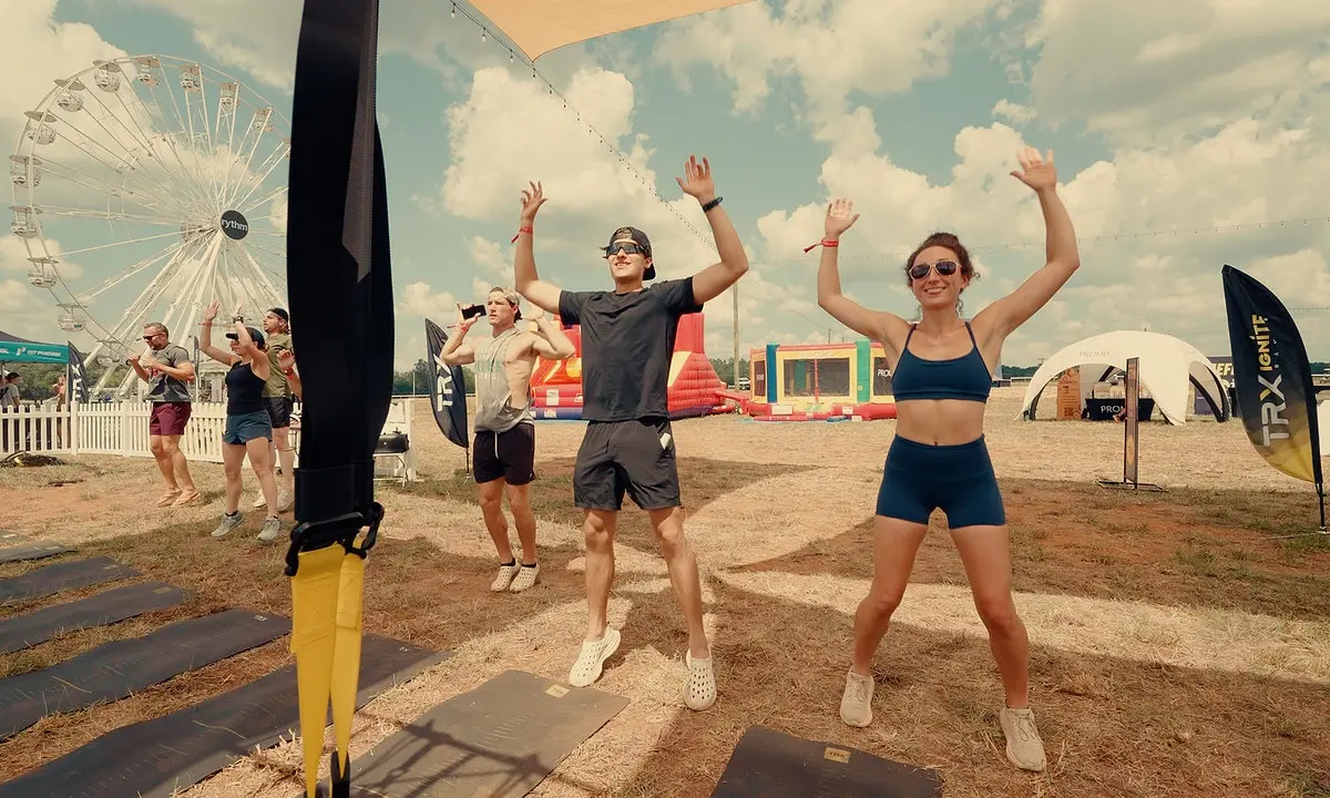 Group performing TRX warm-up at outdoor fitness festival