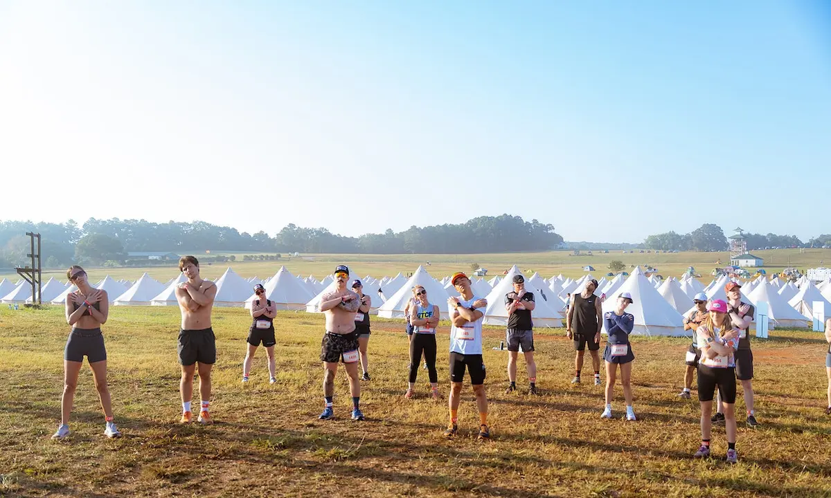 Outdoor group exercising in front of rows of white canvas tents